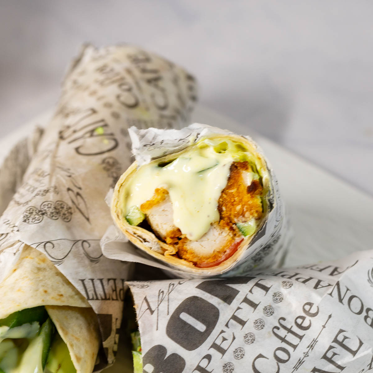 Two chicken and avocado wraps in parchments.