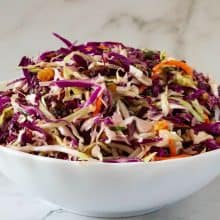 A bowl with salad made with cabbage, carrots, dried fruits.