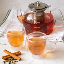 Two cups of spiced ginger tea with a kettle.