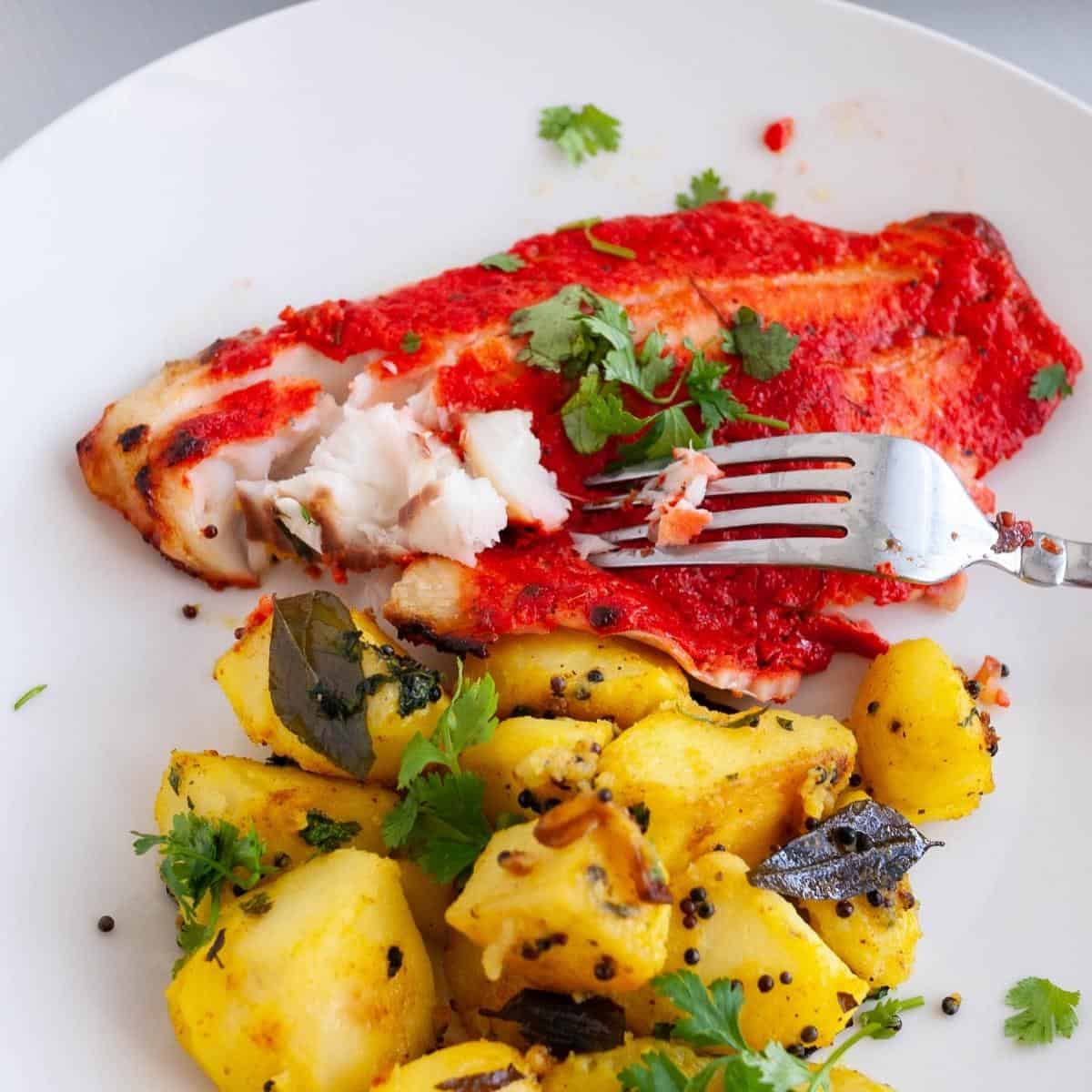 A plate with baked fish in tandoori masala.