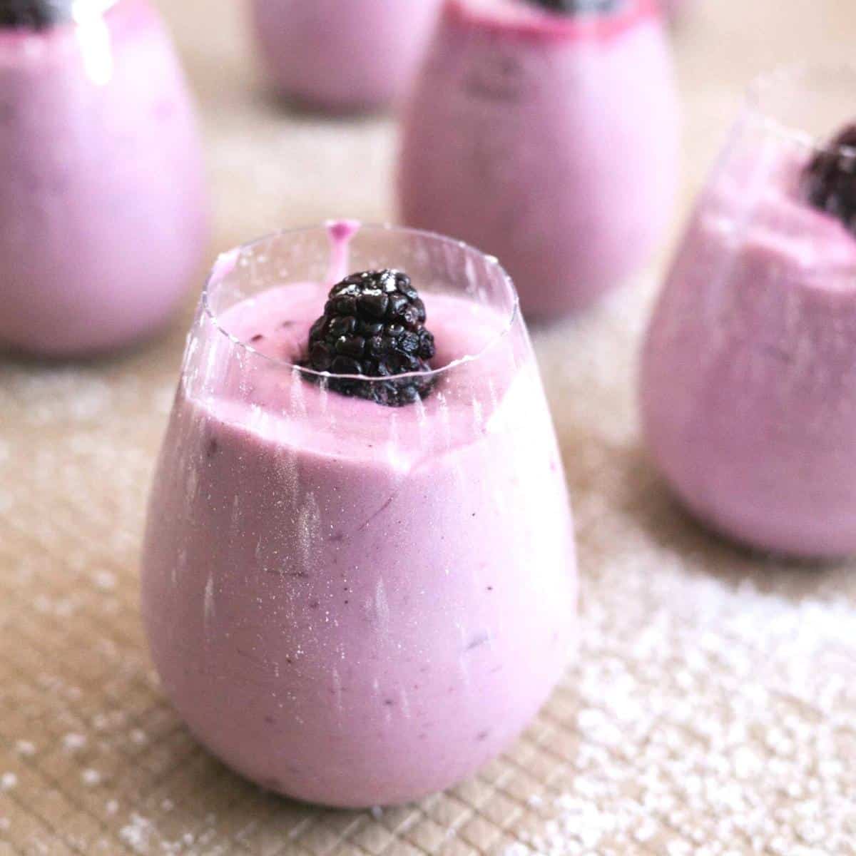 A glass with mousse and a blackberry