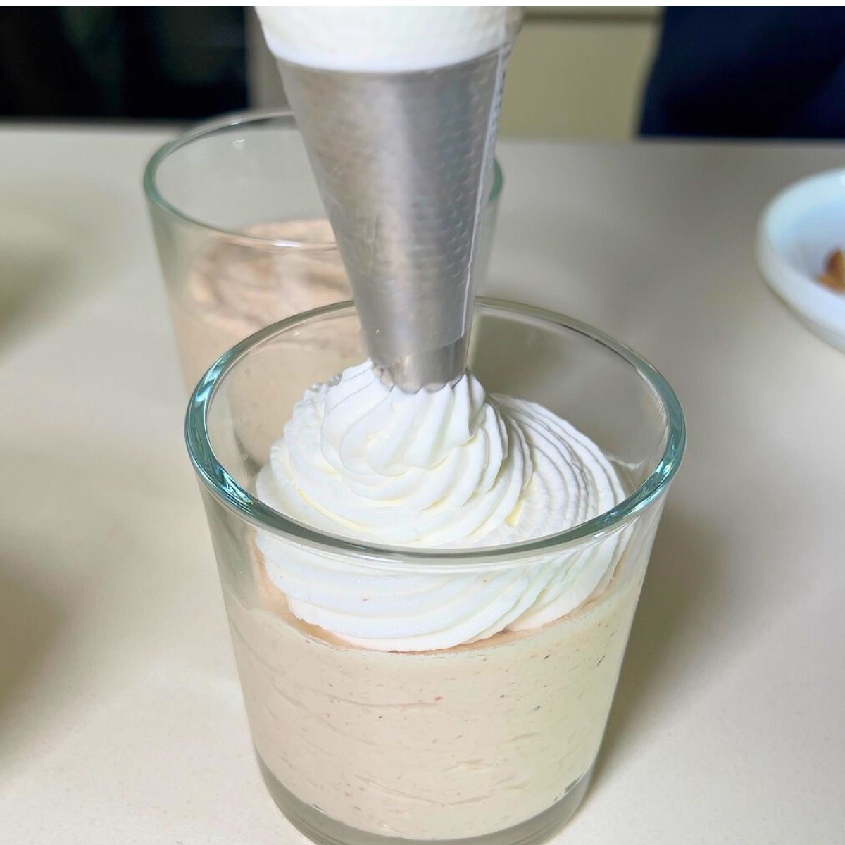 Progress pictures piping whipped cream over a mousse.
