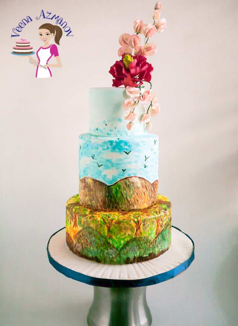 A hand painted cake with sugar flower on top.
