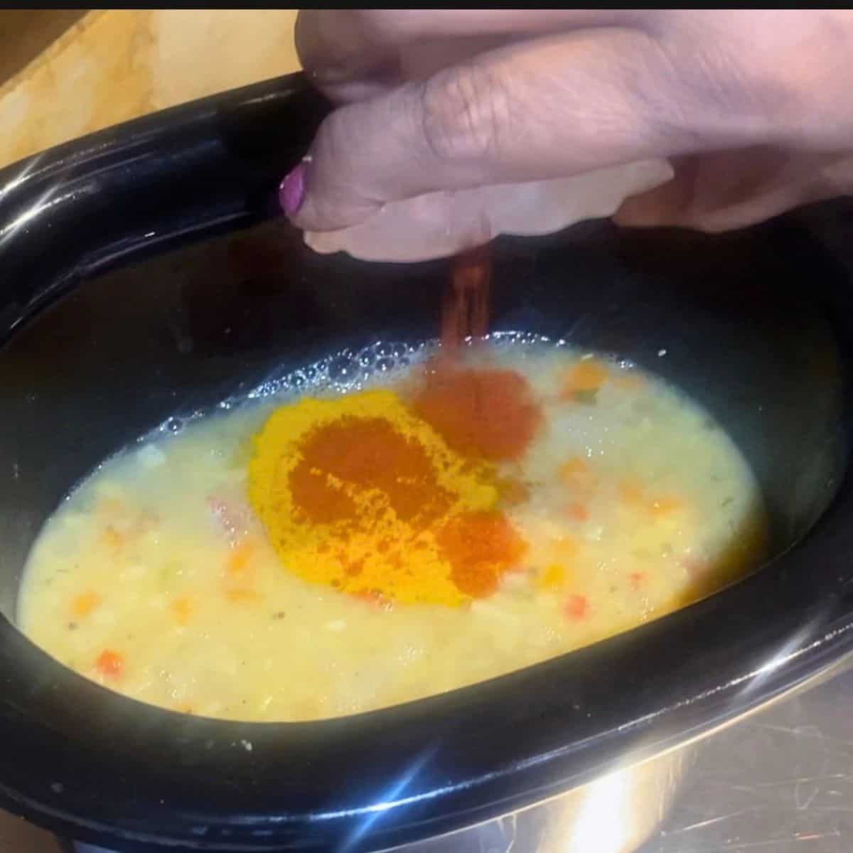Adding turmeric and paprika to the slow cooker.