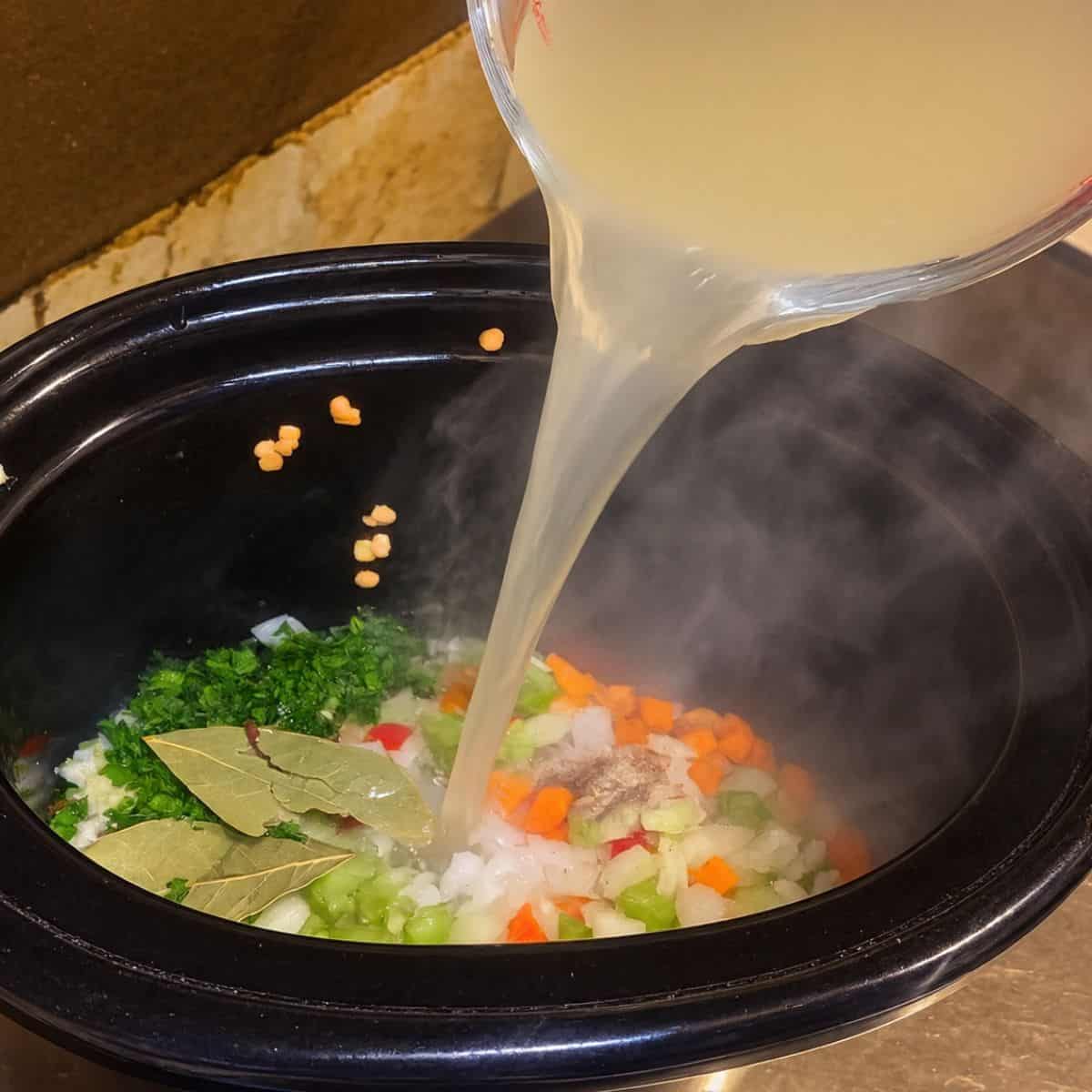 Adding bone broth to the slow cooker.