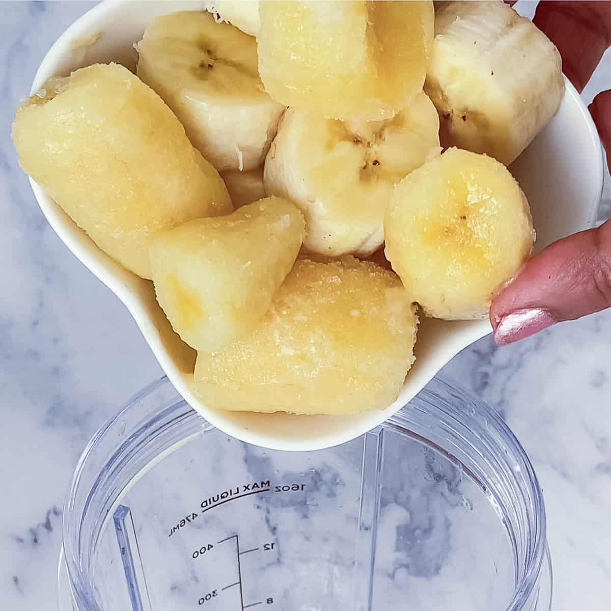 Adding frozen banana to the blender.