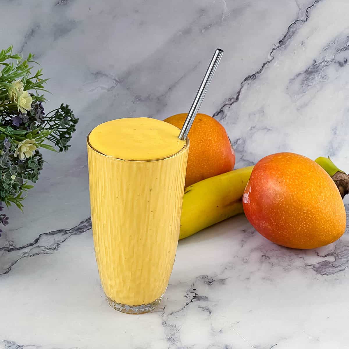 A tall glass with mango smoothie.