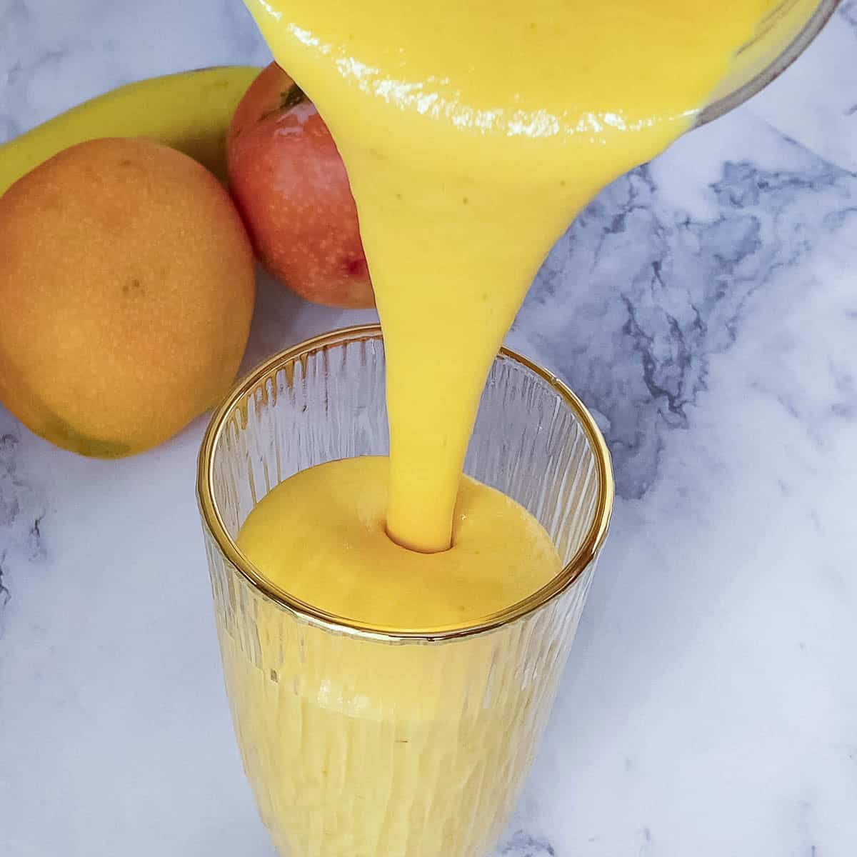 Pouring the mango smoothie into a glass.