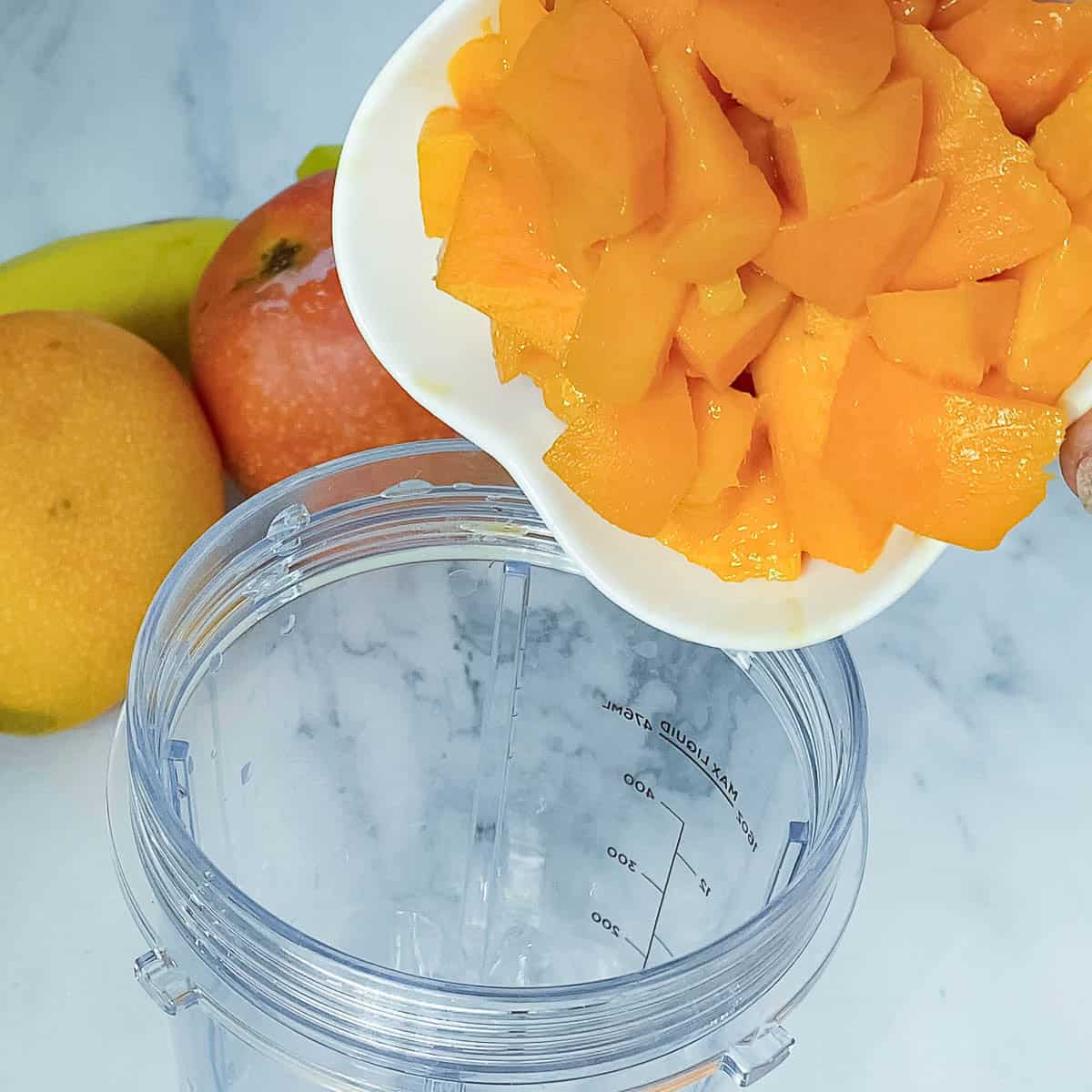 Adding mango to the blender.