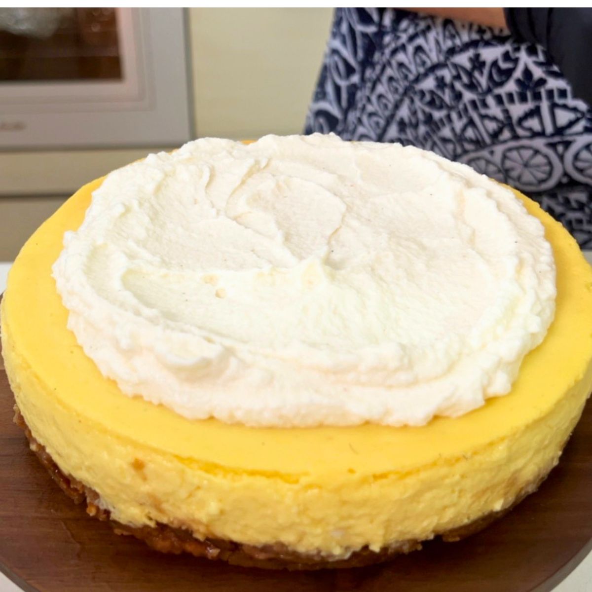 Top a mango cheesecake with whipped cream.