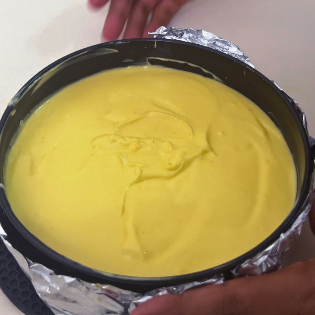 A spring form pan with mango cheesecake batter.