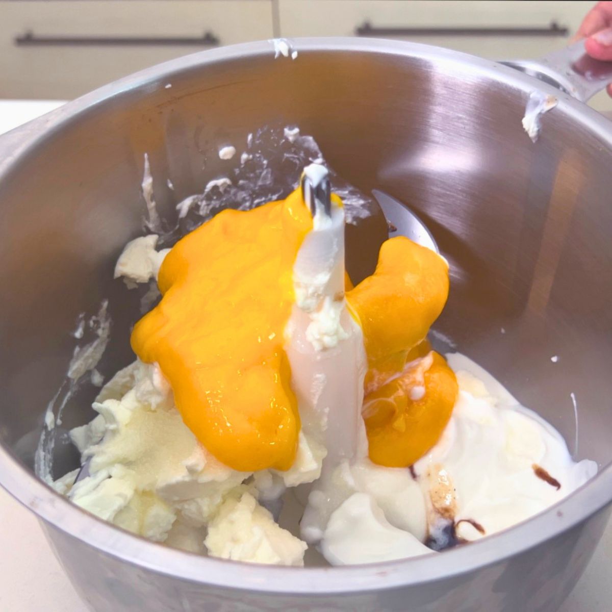 A food processor with mango cheesecake batter ingredients.