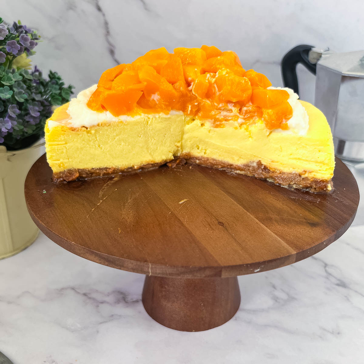 A cake stand with mango cheesecake.