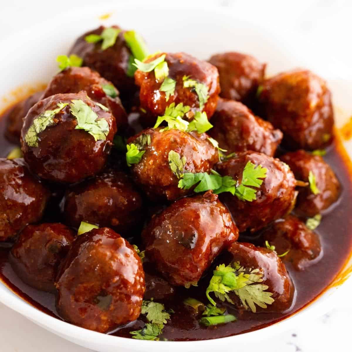 Meatballs in a bowl with sweet and sour sauce.