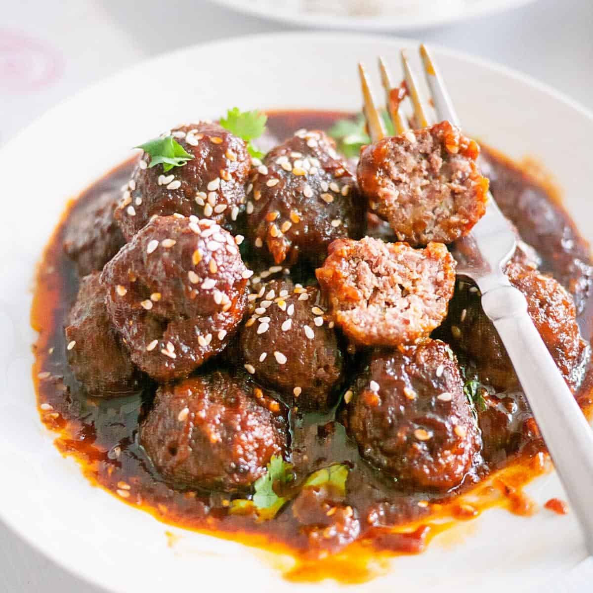 A shallow plate with meatballs and a fork.