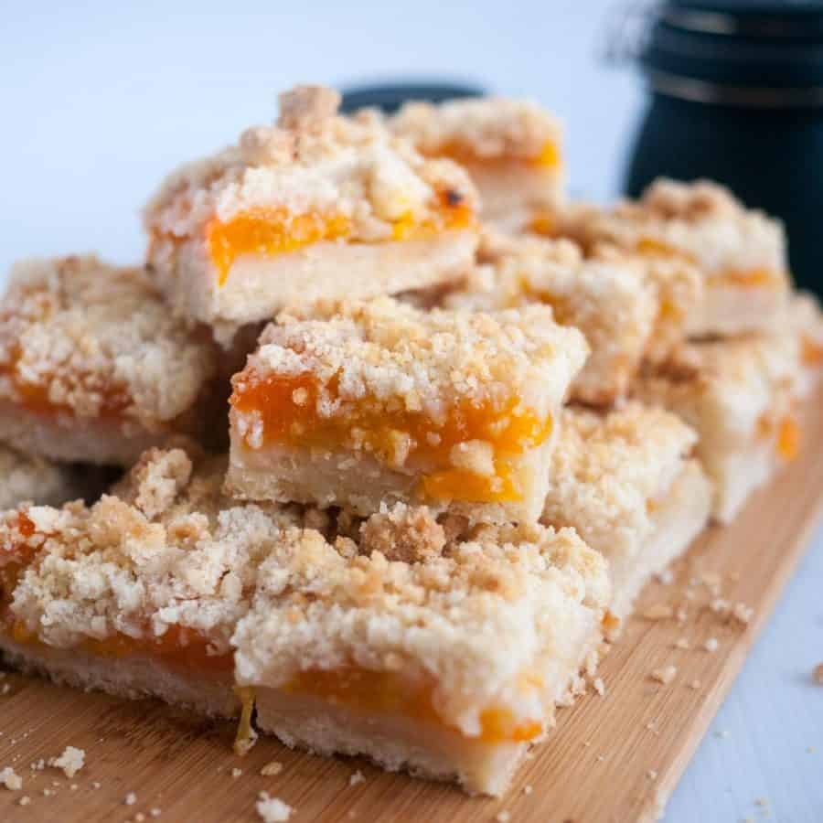 A stack of apricot crumble squares on a wooden board.