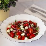 A white bowl with tomato Mozzarella salad.
