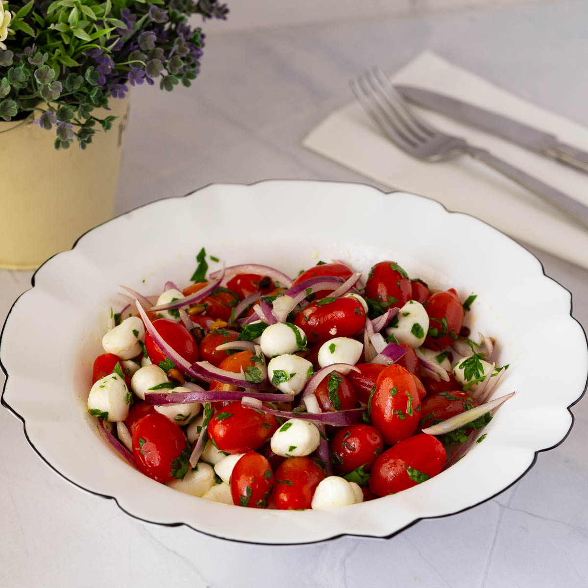 A white bowl with tomato Mozzarella salad.