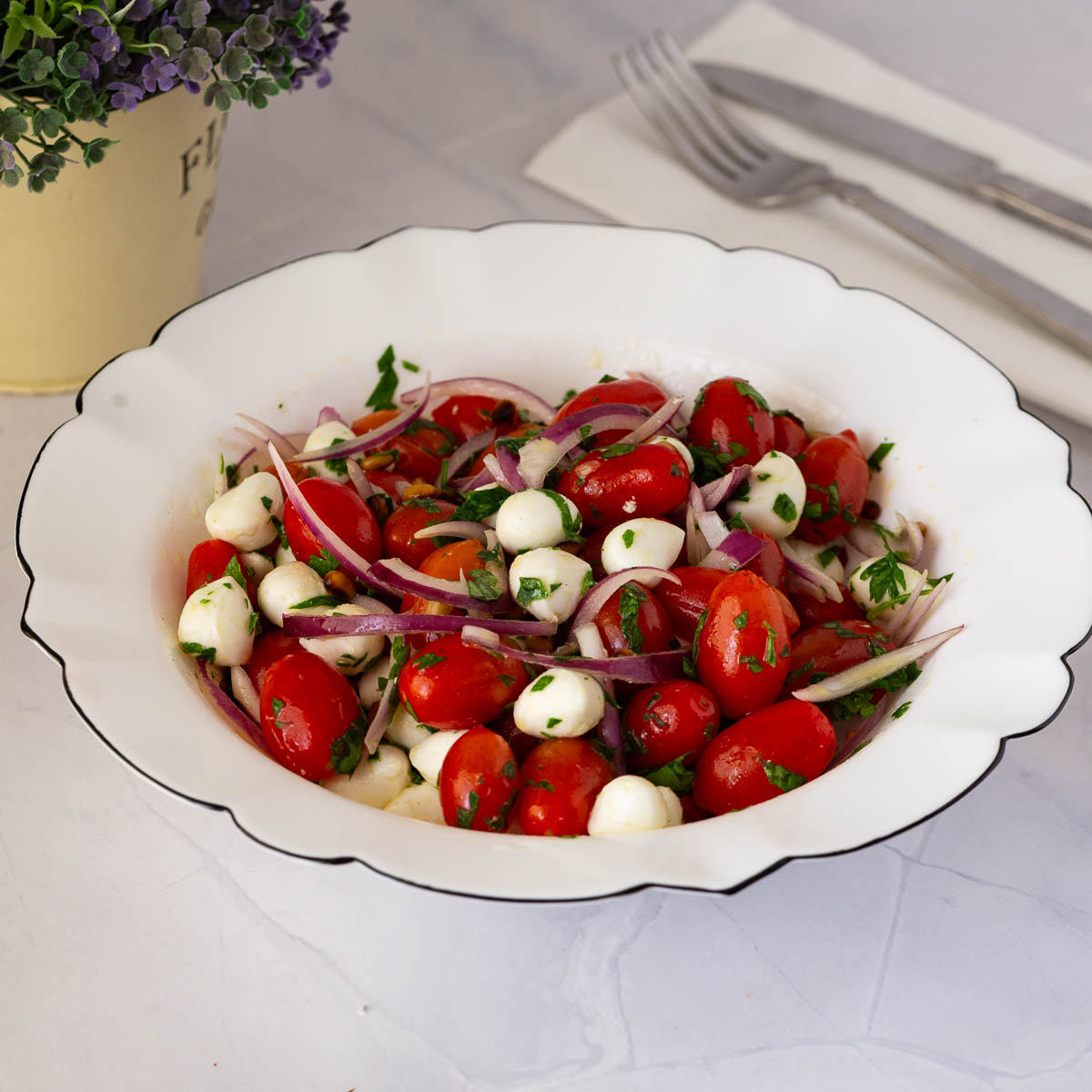 A white bowl with cherry tomato mozzarella salad.