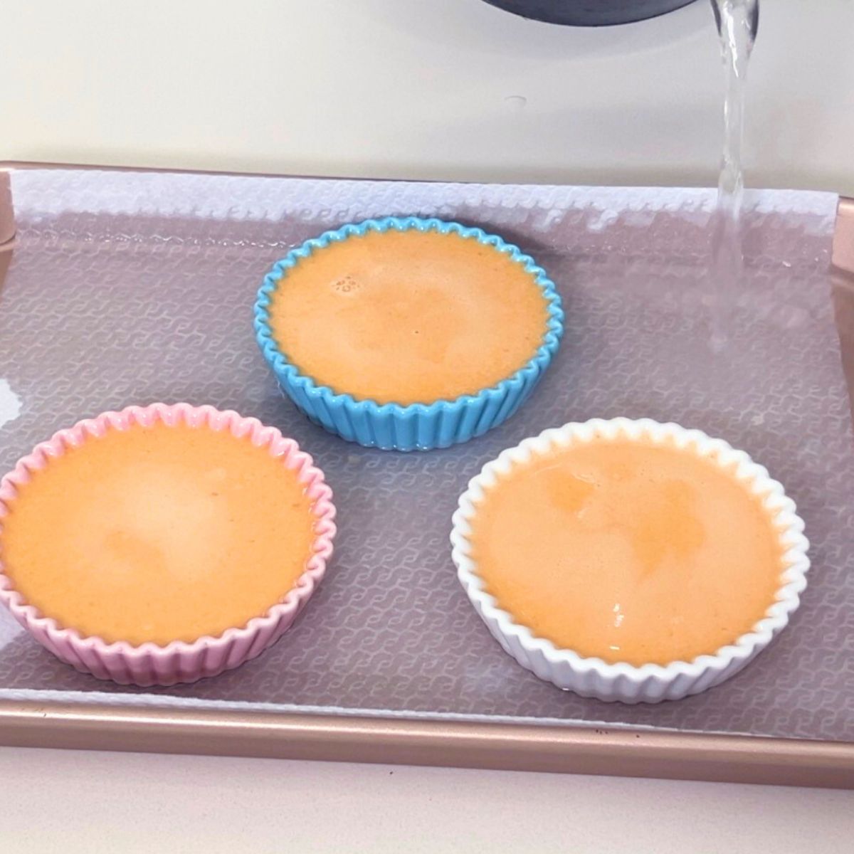 Progress pictures pouring hot water in the baking tray with ramekins.