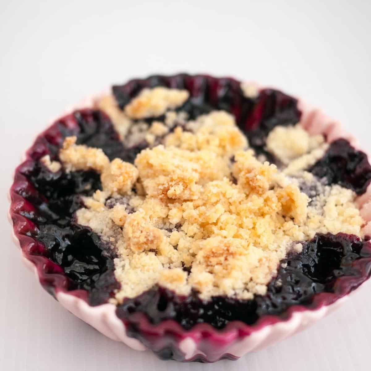 A ramekin with blackberry fruit crumble.