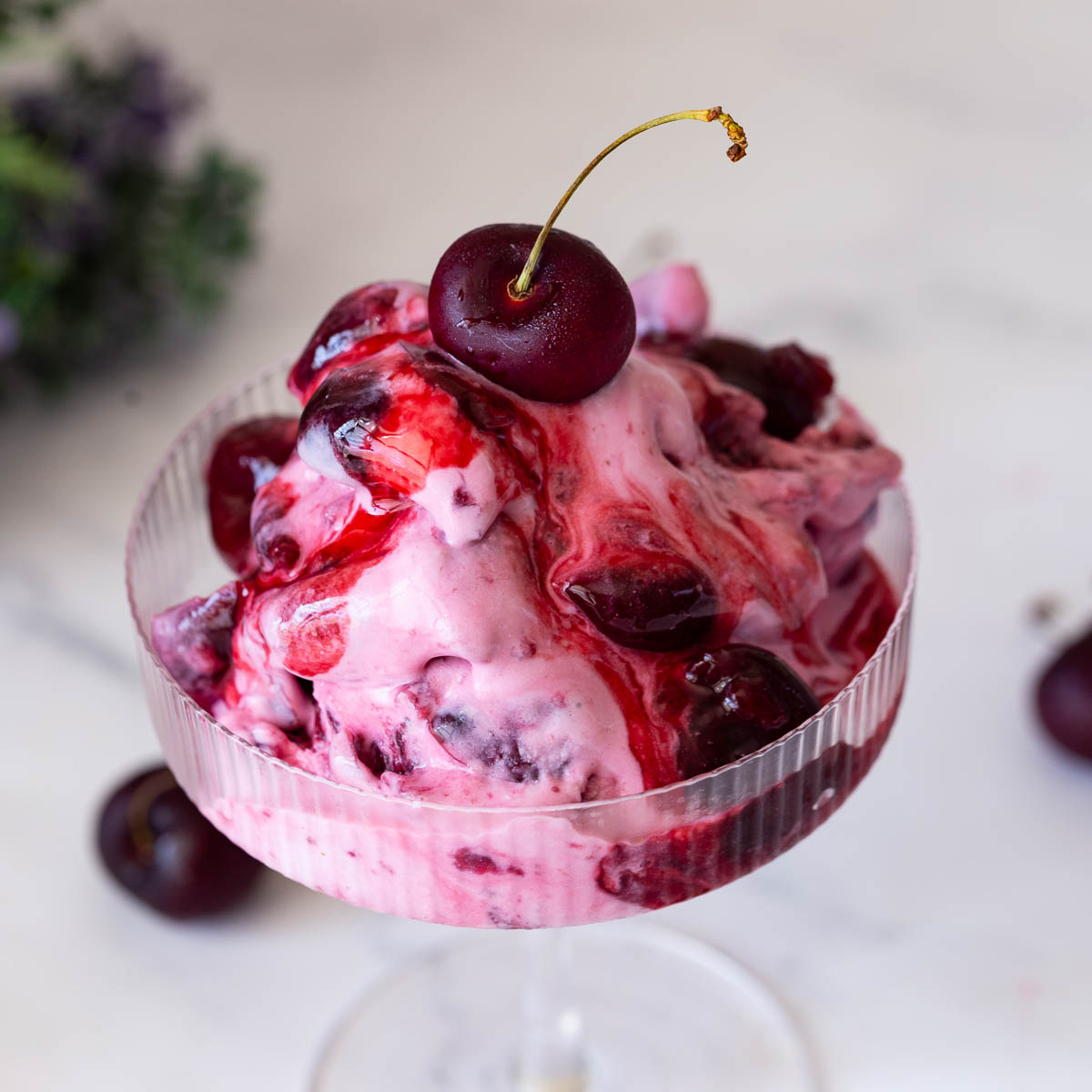 A glass cup with cherry ice cream.