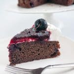 A slice of cherry cake with chocolate and cherry filling.