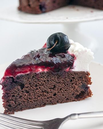 A slice of cherry cake with chocolate and cherry filling.