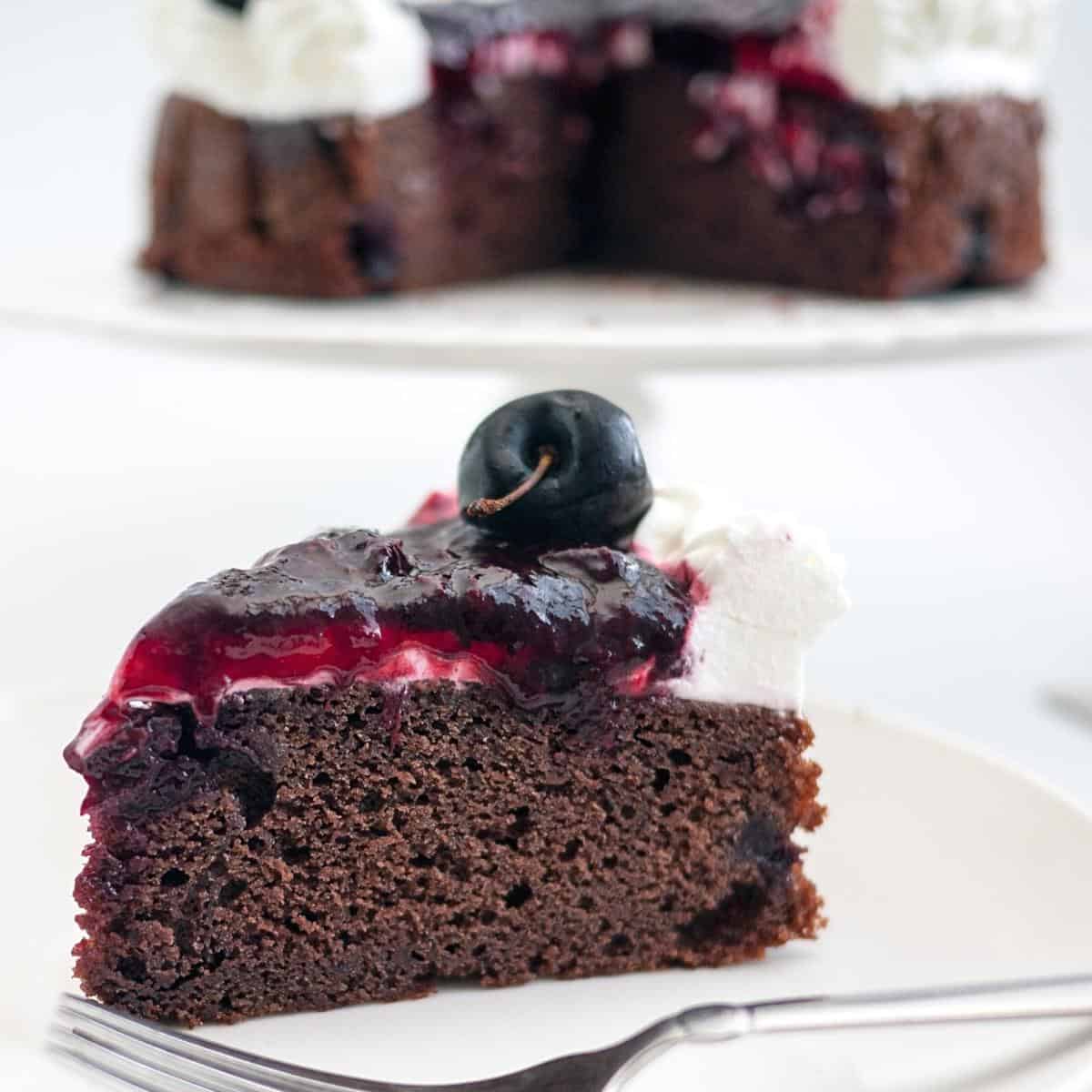 A slice of chocolate cake with cherries filling.
