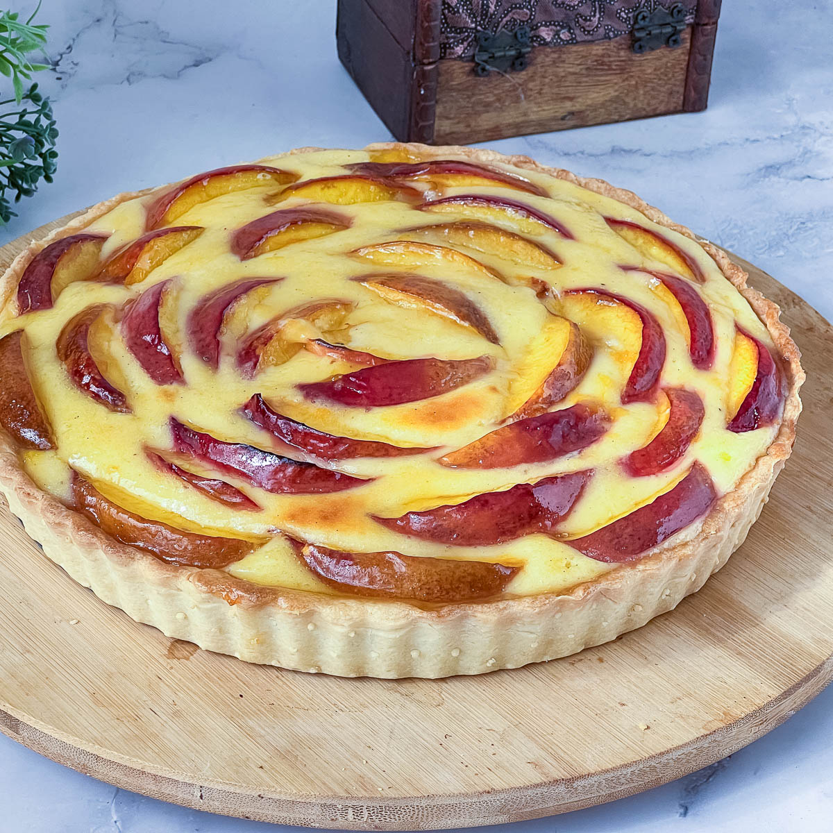 A fresh nectarine tart with cream cheese filling on the table.