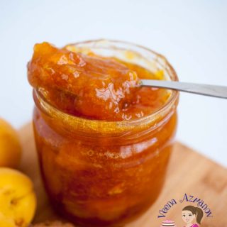 A jar of apricot jam with a spoon in it.