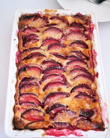 A baking dish with baked clafoutis with plums.