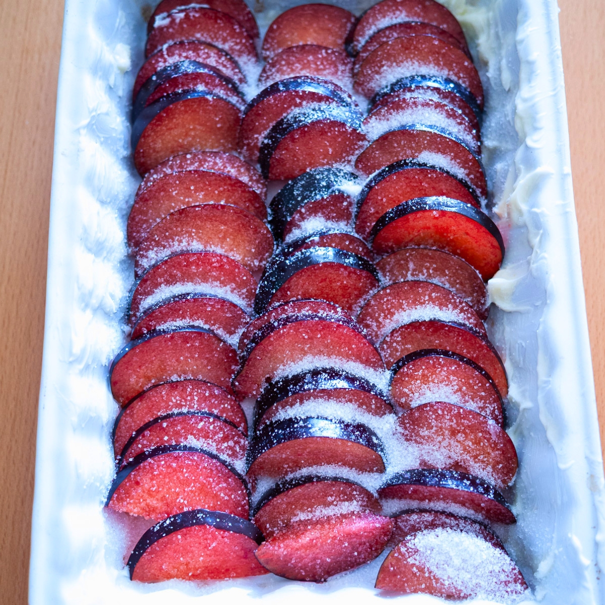 A baking dish with fresh sliced plums.