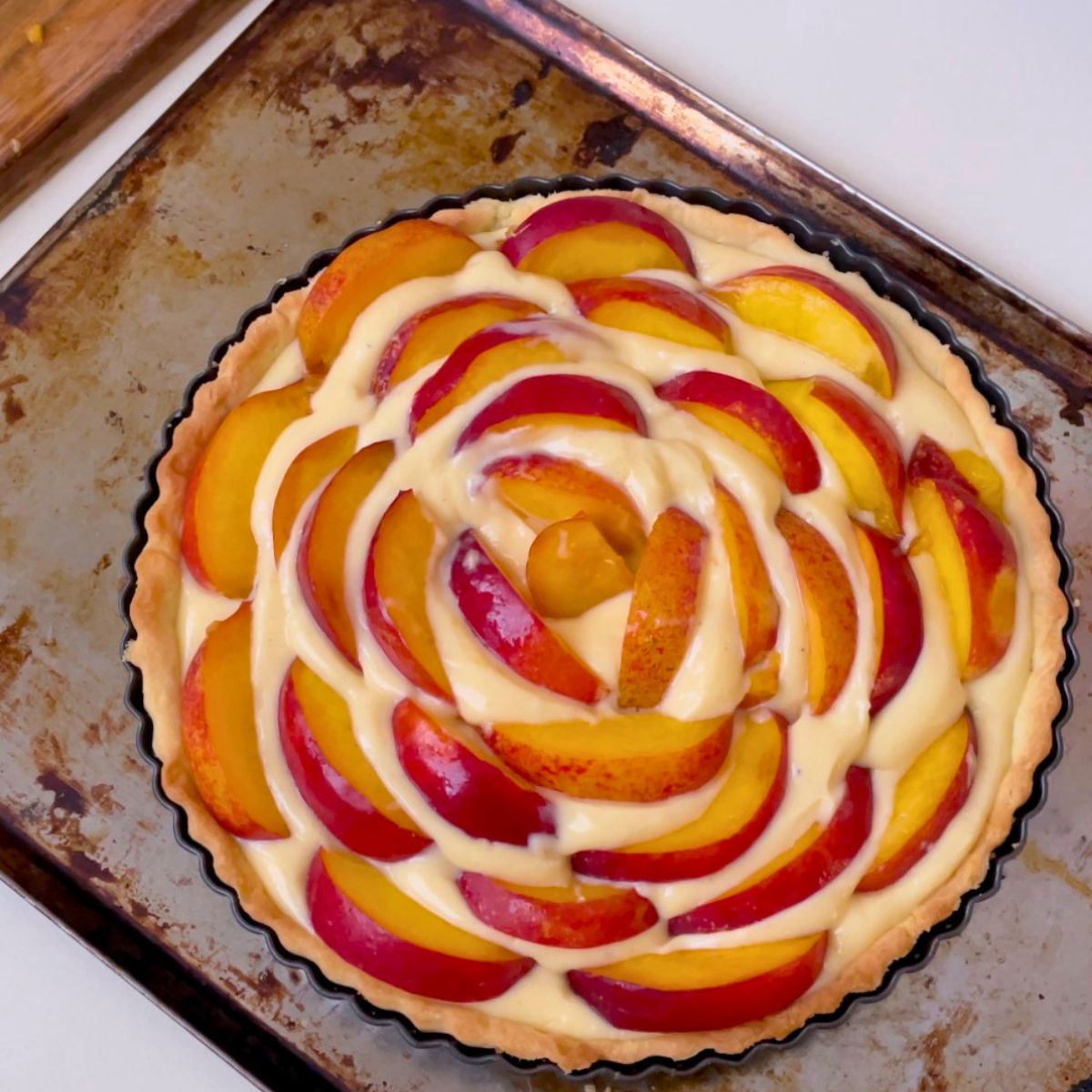 Adding fresh nectarines to cream cheese filling in a tart.