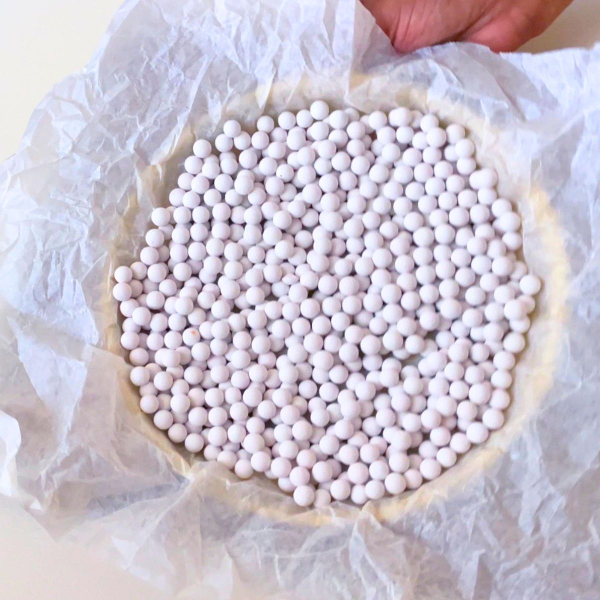 Adding pie weight in a tart crust for blind baking.