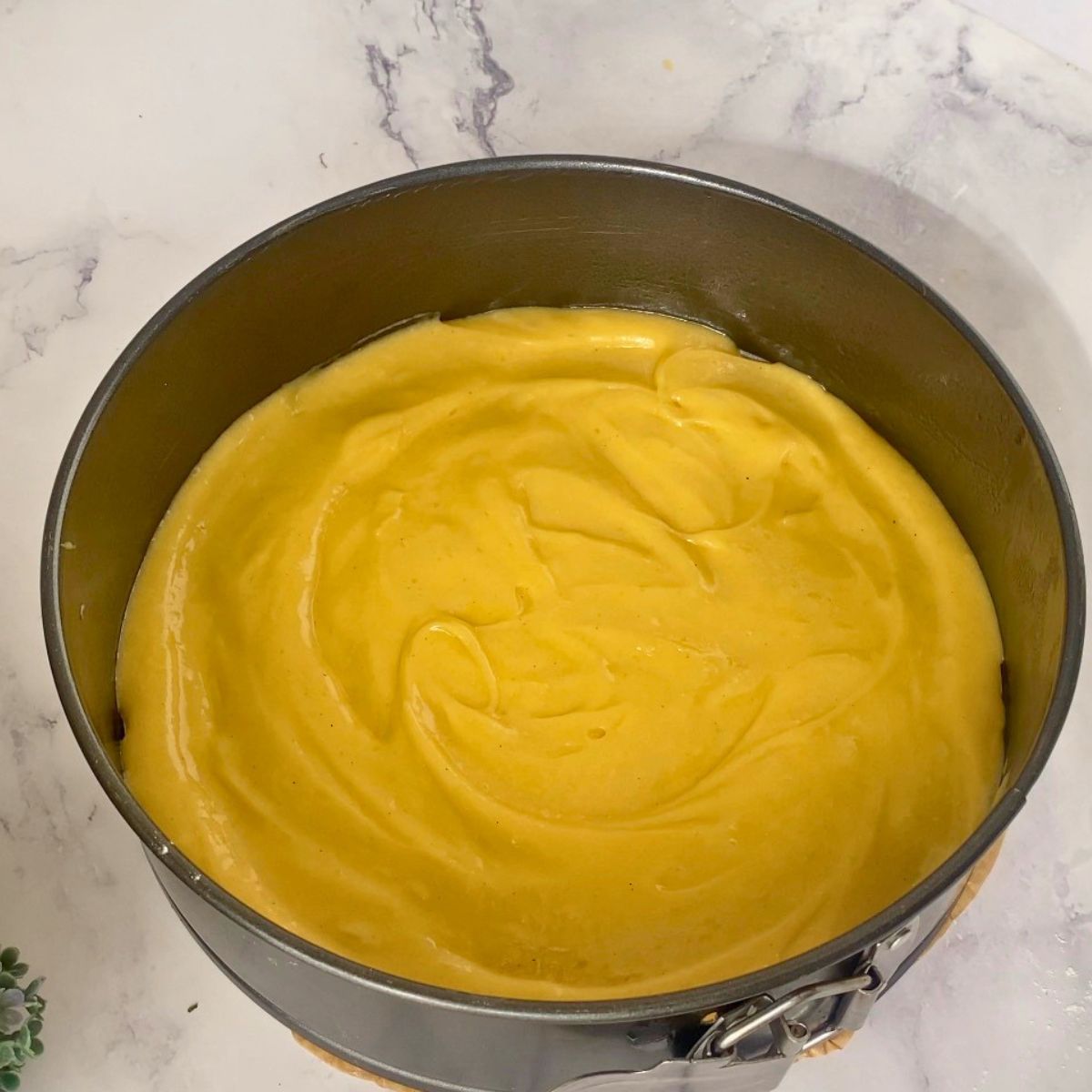 A thin layer of mango cake batter in the pan.