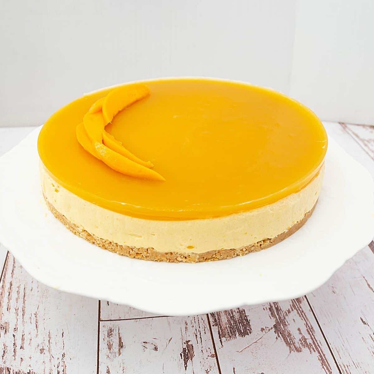 A mango mousse cake on a cake stand.