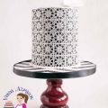 A black and white lace decorated cake on a stand.