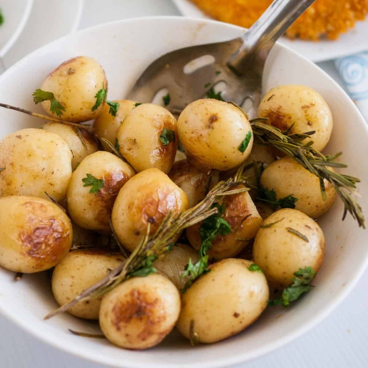 A white bowl with roast potatoes