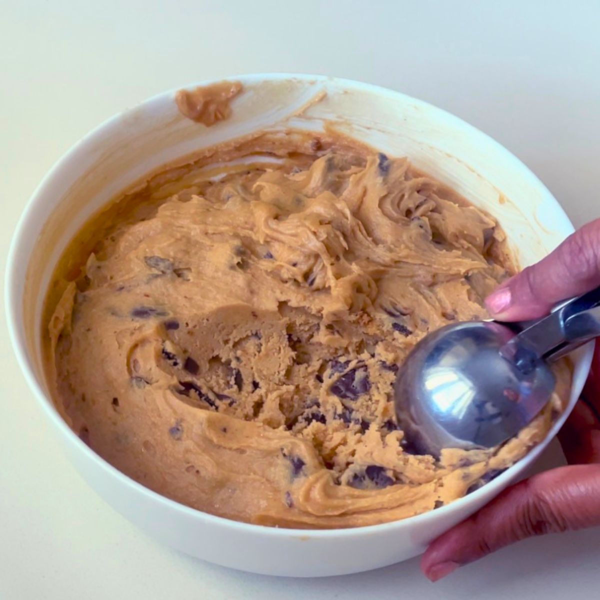 A white bowl with chocolate chip cookie dough.