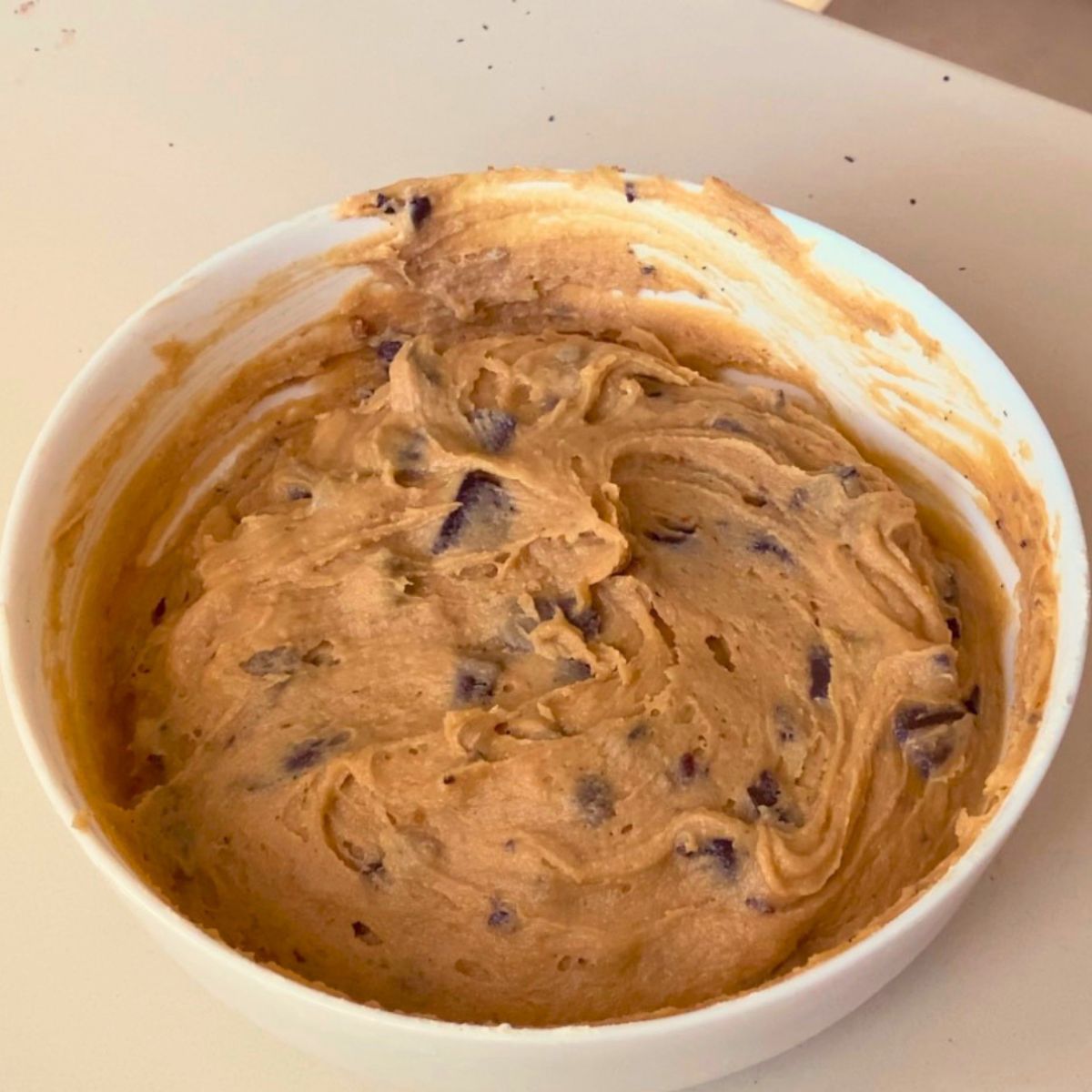 A white bowl with chocolate chip cookie dough.