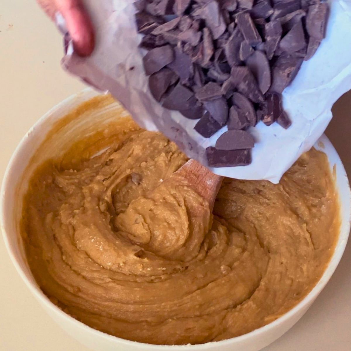 Adding chopped chocolate to the chocolate chip cookie dough.