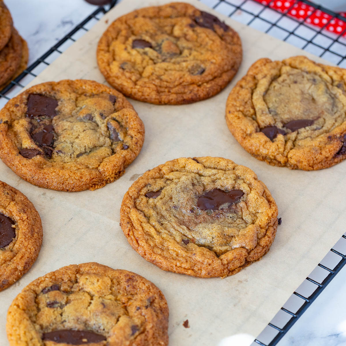 Thin crispy chocolate chip cookies on a wire rack.