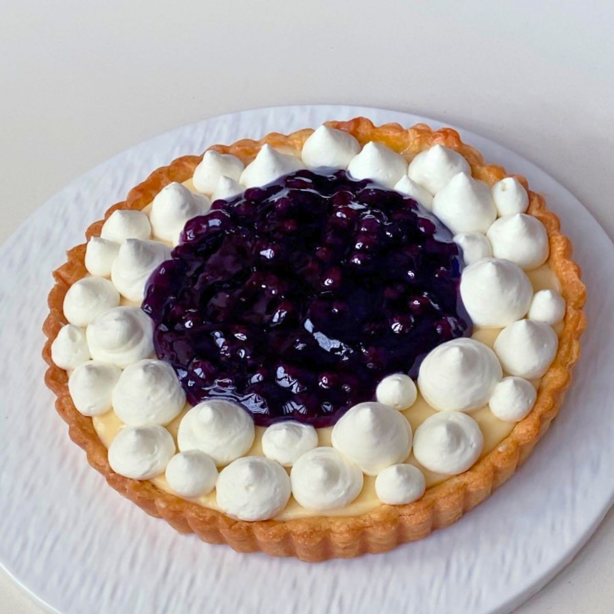 Piping the whipped cream on to the blueberry tart.