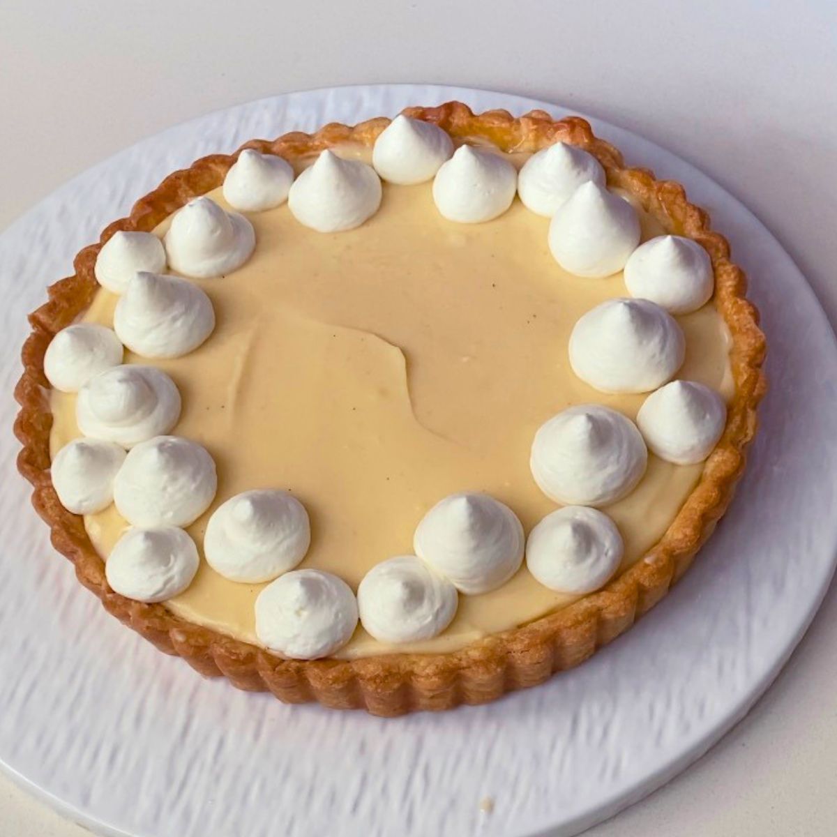 Piping the whipped cream on the blueberry custard tart.
