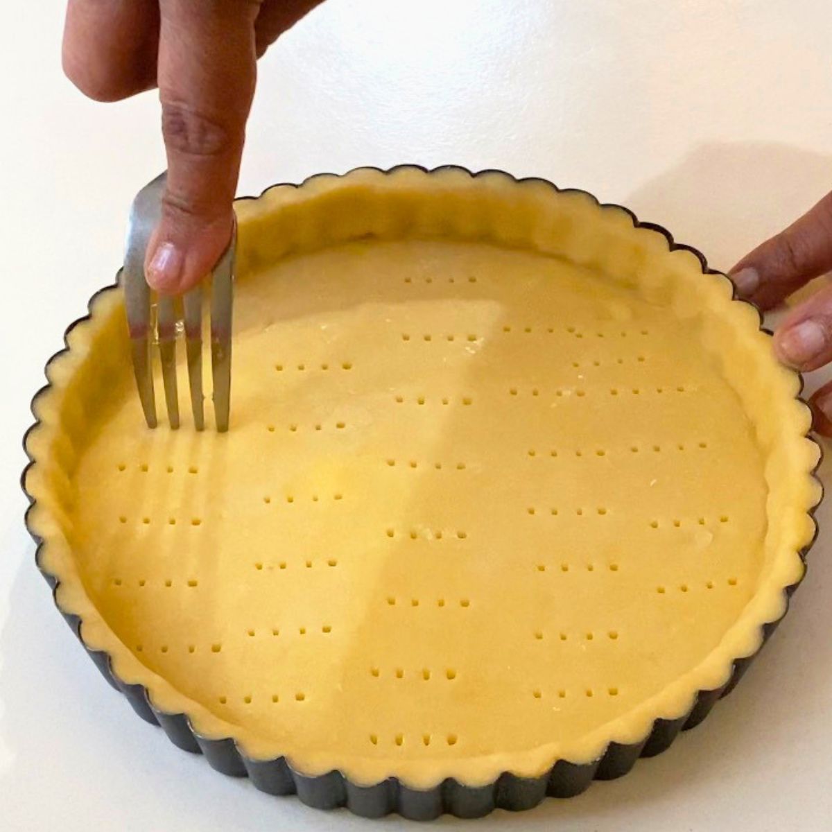 Docking the tart crust with fork before baking.