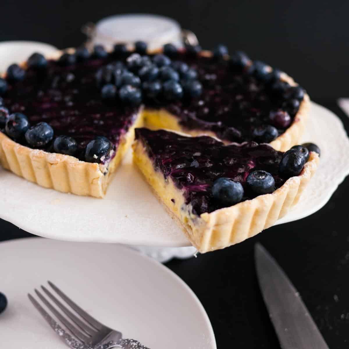 Blueberry tart on a cake stand.