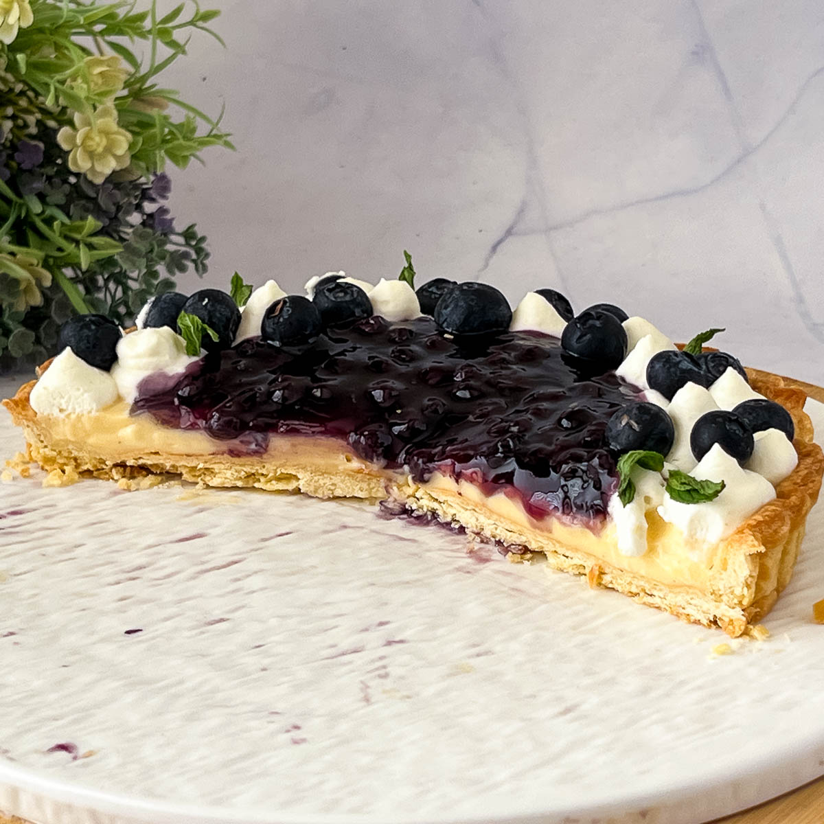 A sliced blueberry tart on the cake stand.