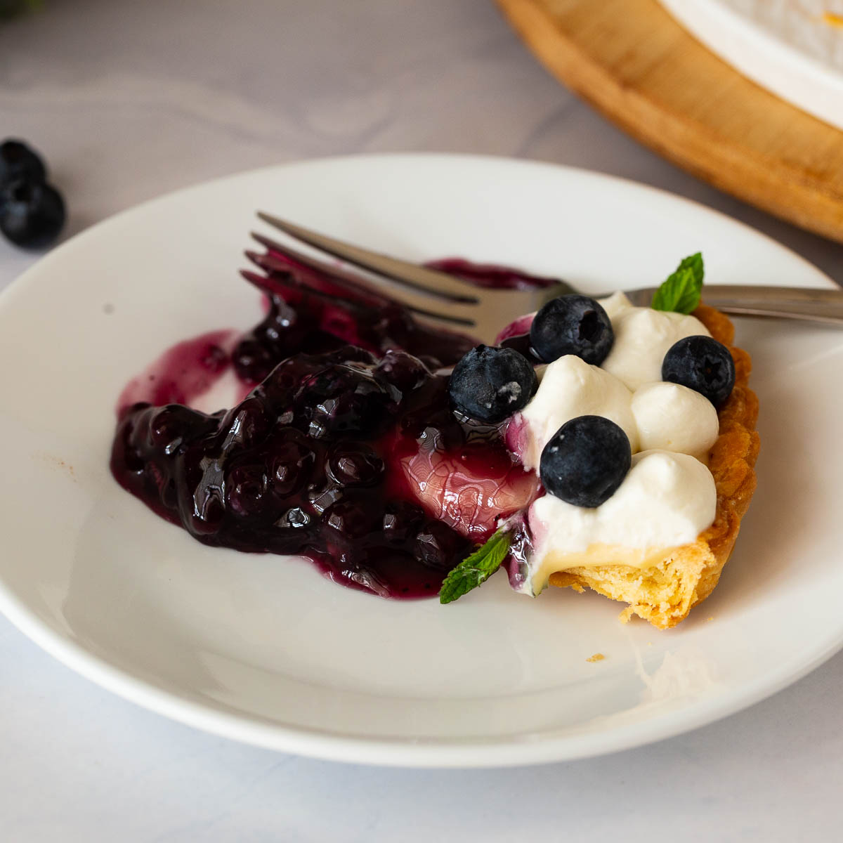 A white plate with fresh blueberry tart.