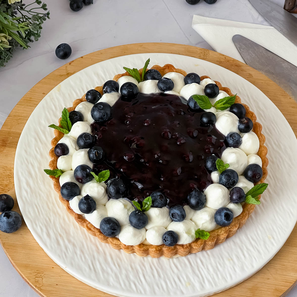 Blueberry tart on display with fresh blueberries.